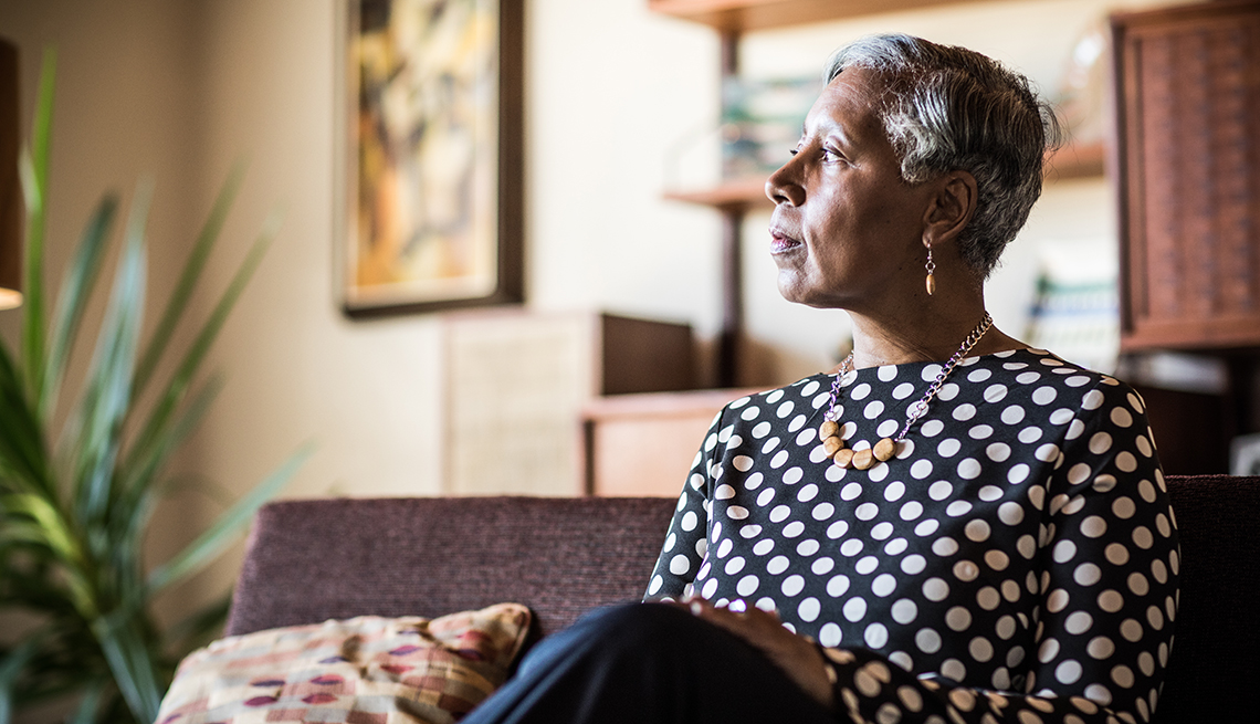 Woman sitting on a couch at home, looking lonely