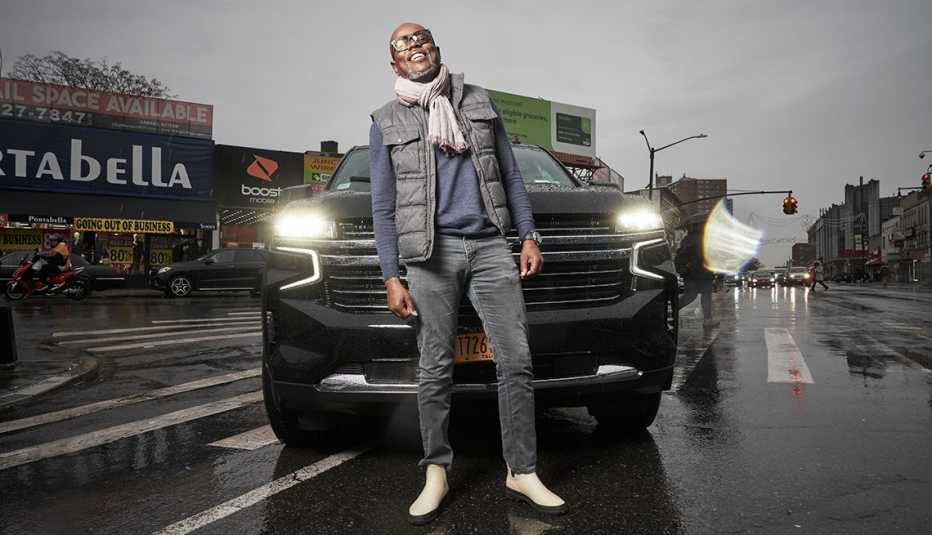 uber driver fritz sam stands in front of his vehicle