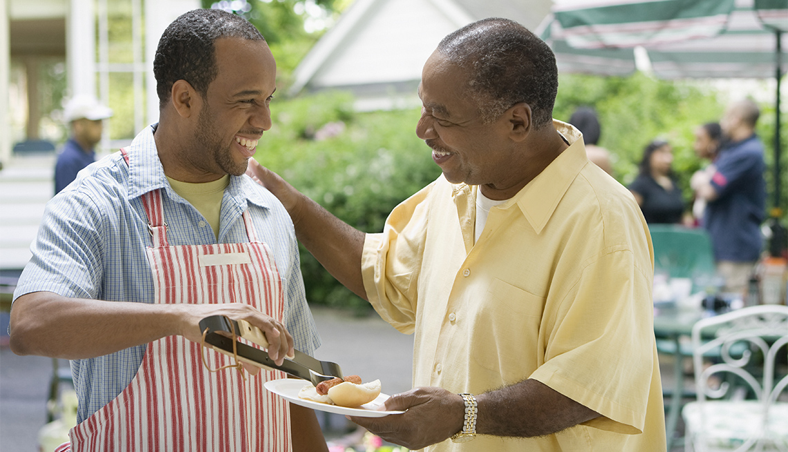 Son serves father a hotdog at a BBQ