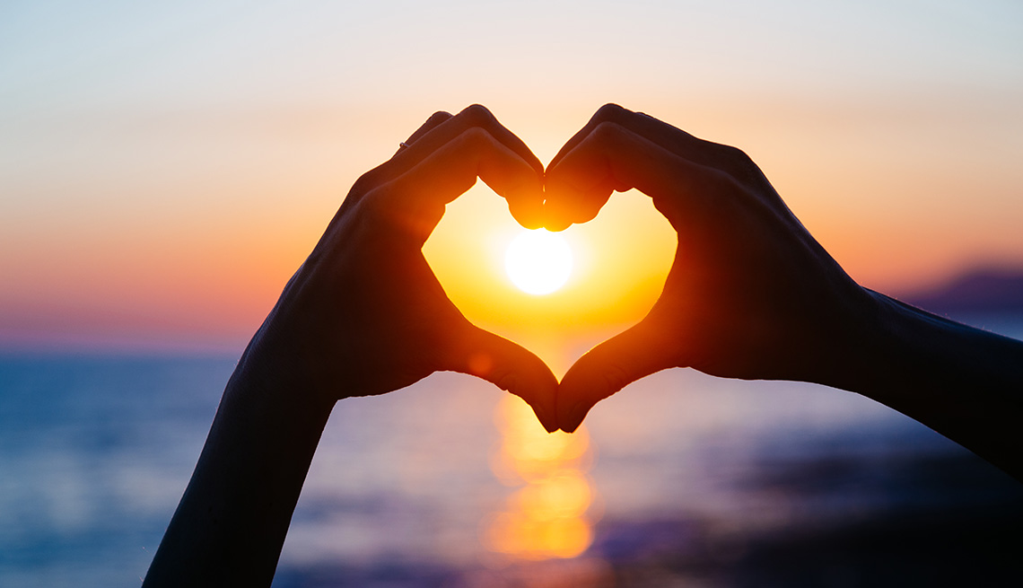 hands making heart silhouette in sunset