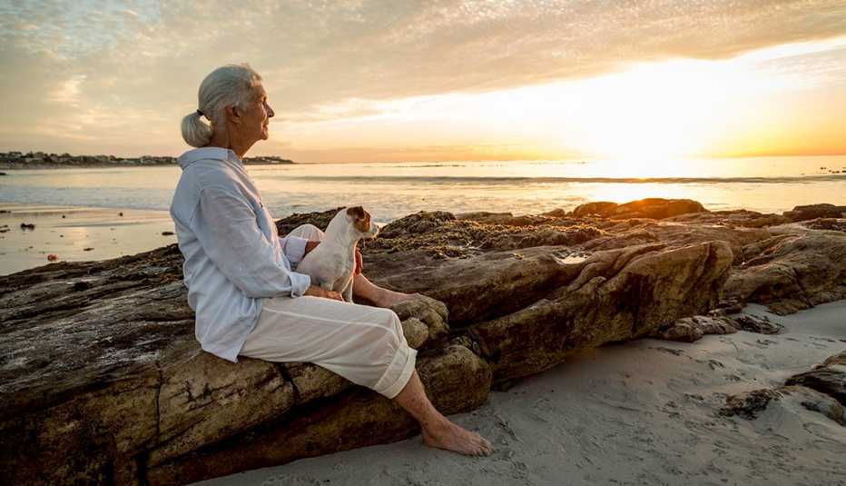 woman sitting with her dog on the beach