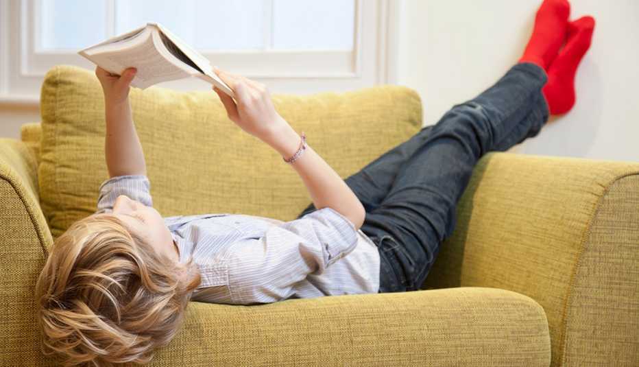 pre teen boy lounging in a chair reading a book