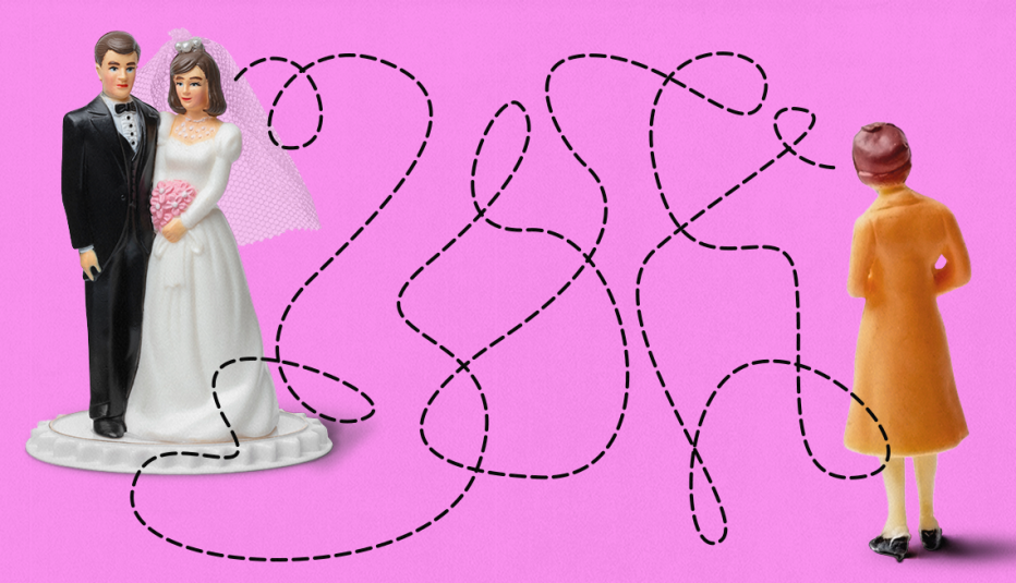 a woman in a coat looks at a bride and groom figurine