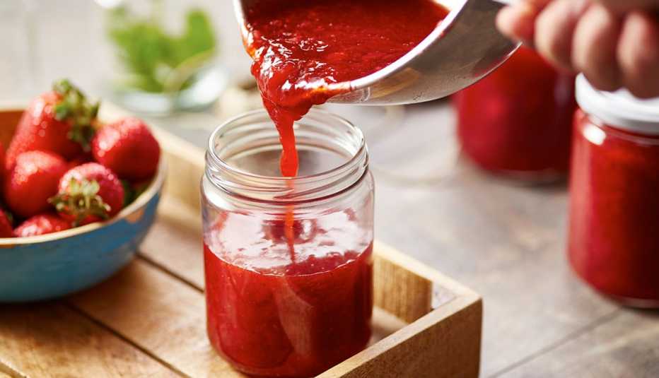 a person pours jam into a jar
