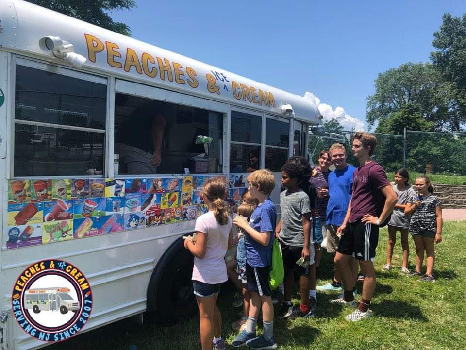Peaches and Ice Cream truck with a line of people buying ice cream