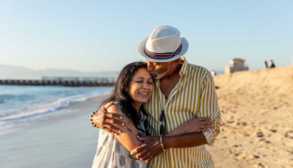 a couple embraces while they walk along a beach