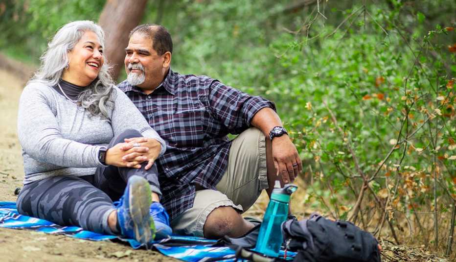 A couple enjoying a picnic on a blanket in the woods. A couple enjoying a picnic on a blanket in the woods.