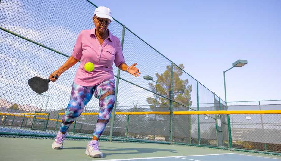 woman serving a pickleball on a court