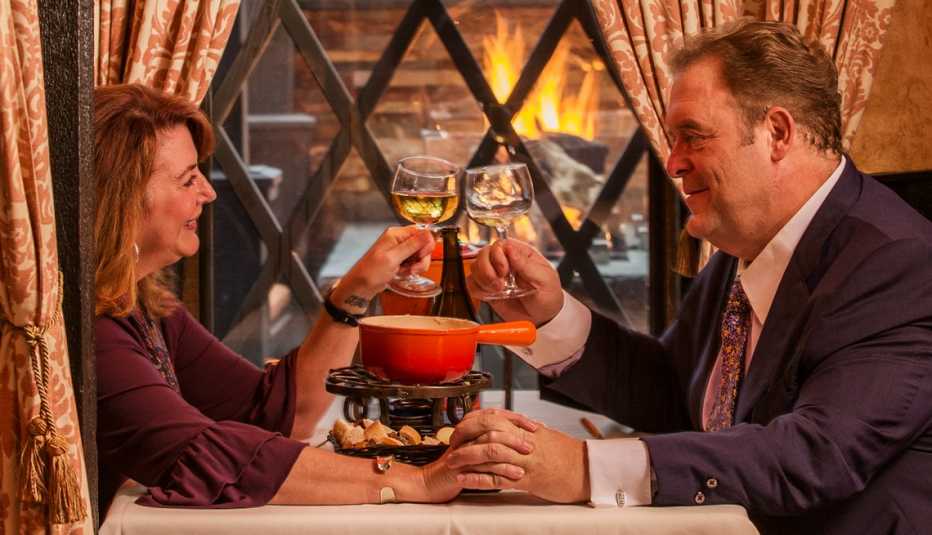 jeff and darla lawler seated at the table they got engaged in and clinking wine glasses as they share fondue