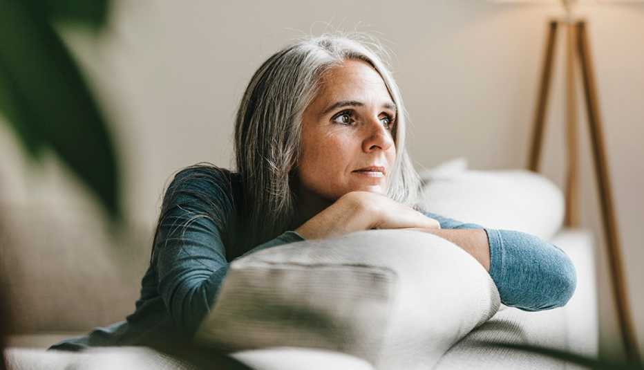 A woman looking outside a window while sitting on her couch