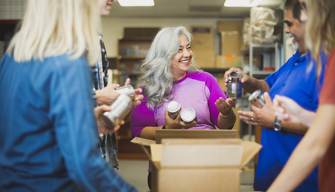 A diverse team fills boxes with food cans