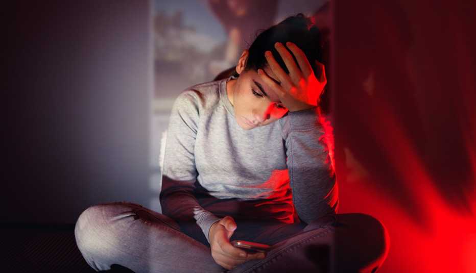 teen girl looking at phone sad