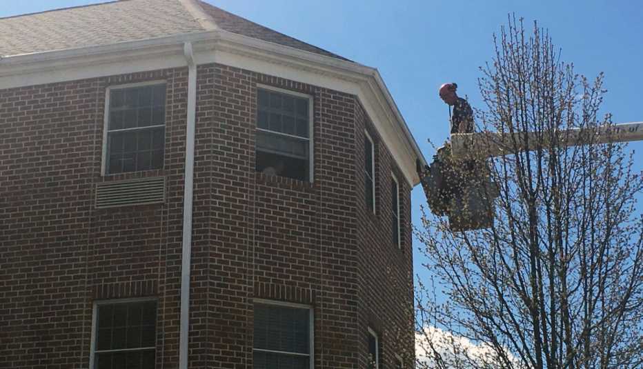 a man in a bucket truck visits a resident on a third level floor of an assisted living facility