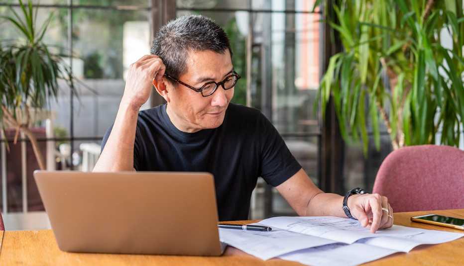 Man looking at a computer and paperwork as he plans his own funeral