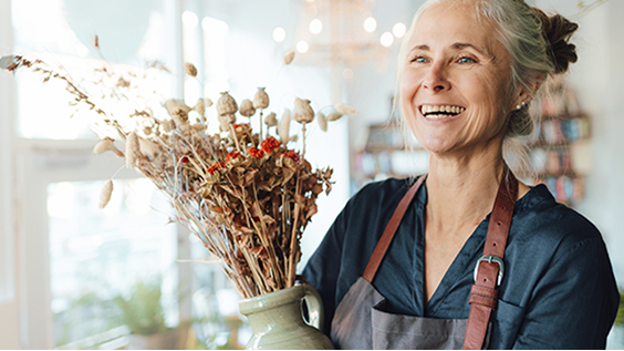female flower shop owner smiling and holding a flower arrangement