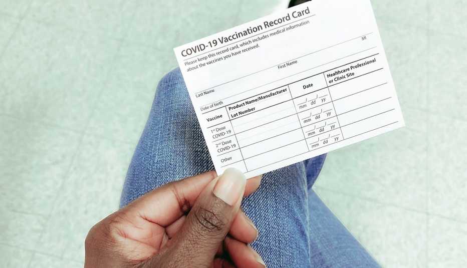 High angle view of person's hand holding COVID-19 vaccination record card High angle view of person's hand holding COVID-19 vaccination record card