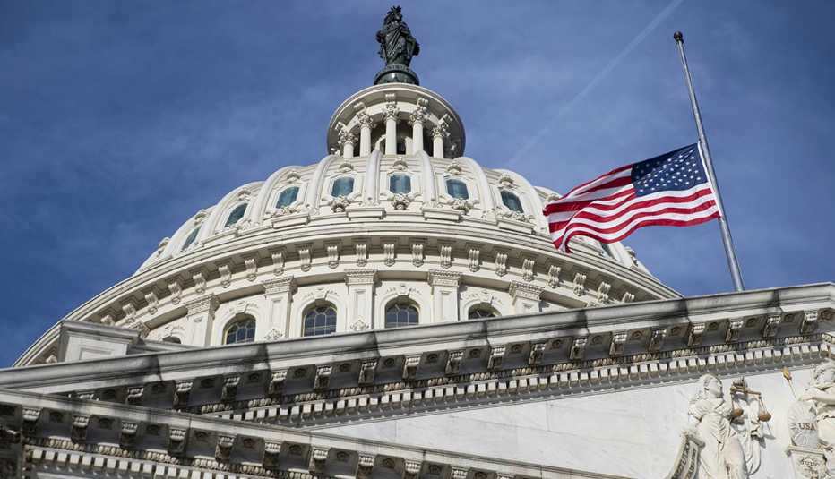 An American flag at half mast in honor of the 500,000 American lives lost to Covid-19 at the U.S. Capitol building in Washington, D.C., U.S., on Friday, Feb. 26, 2021. The House is poised to pass Democrats' $1.9 trillion Covid-19 stimulus, but a ruling late yesterday by a Senate official dealt a major blow to prospects that the final legislation will include a hike in the U.S. minimum wage to $15 per hour. 