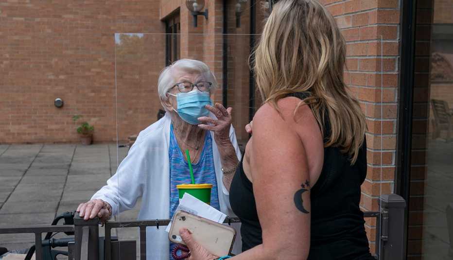 Two women talk to each other with a protective barrier between them