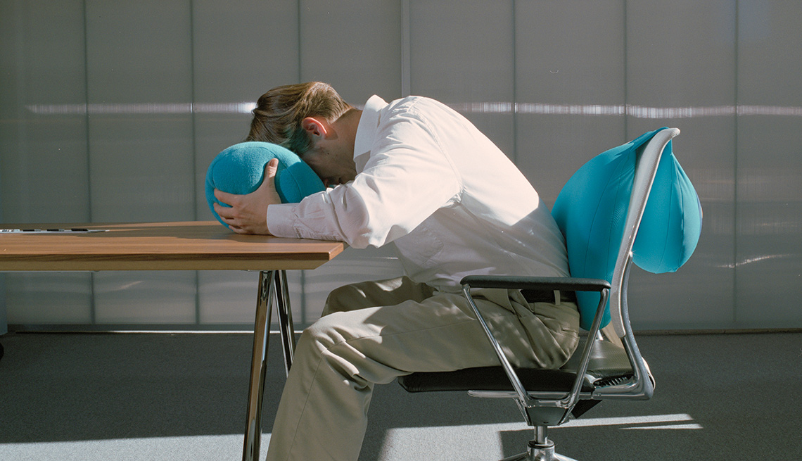 man sitting at desk with face in a pillow