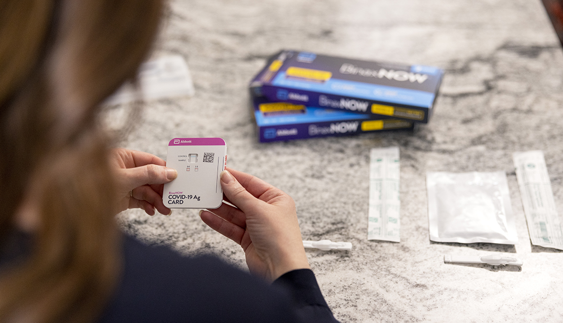 a woman reads the directions for the abbott binax rapid covid test