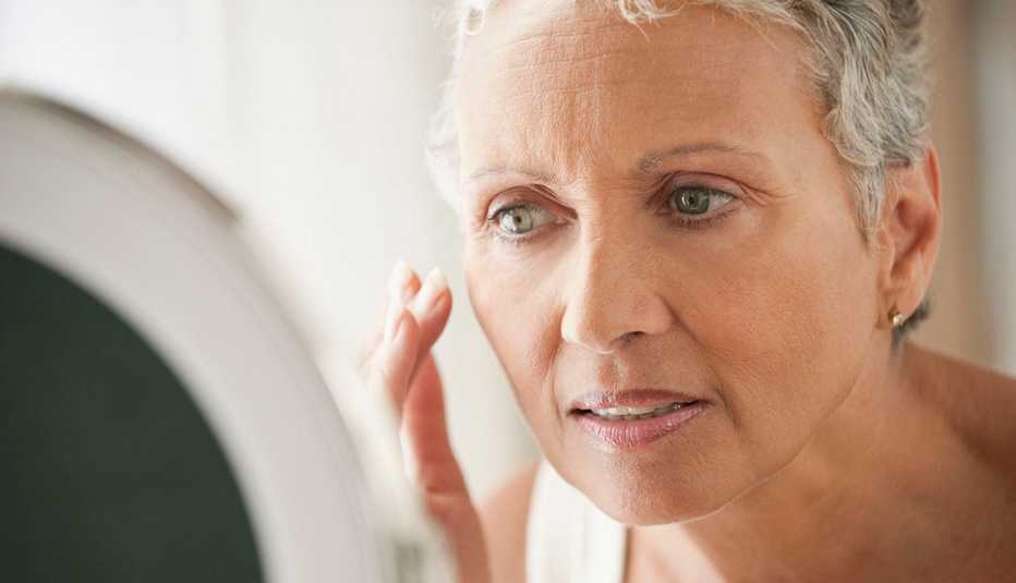 woman looking at her face in a mirror