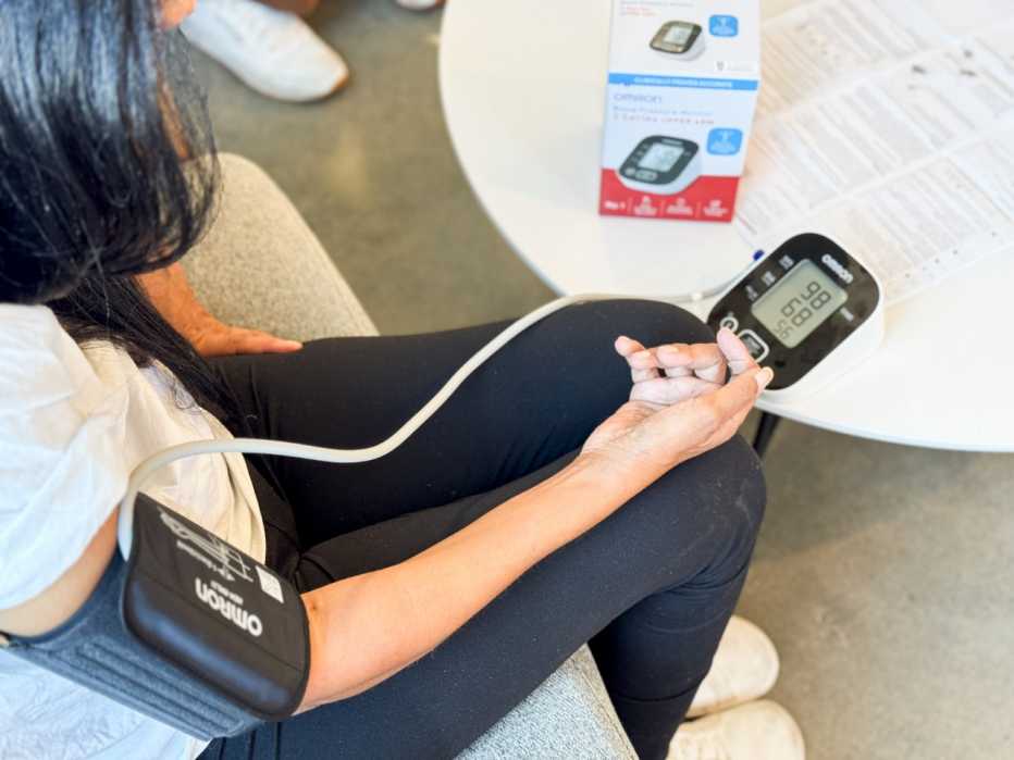 Woman sits and takes a blood pressure reading using the Omron 3 Series blood pressure monitor