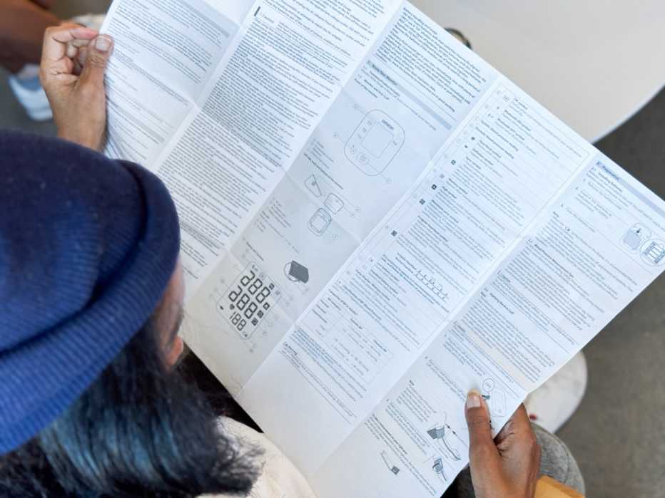 A woman reads the user manual of a blood pressure monitor.