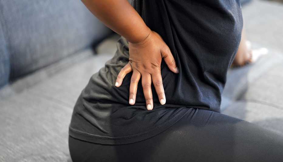 African American woman on a bed grabbing her flank in pain due to bladder cancer 