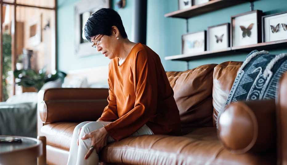 woman seated on a couch with knee pain