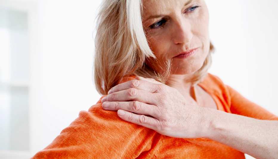 Woman massages shoulder while in pain