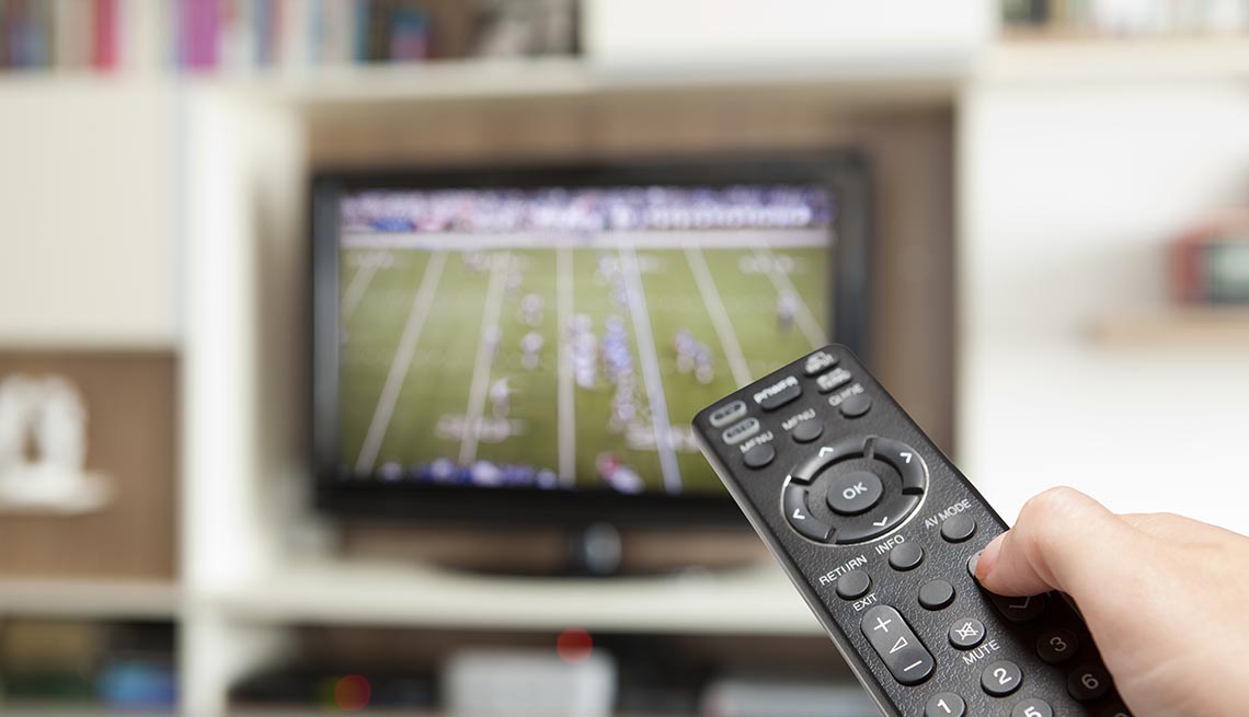watching football with TV remote control in hand