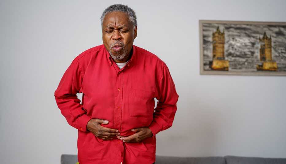 man is exhaling and holding his painful stomach.