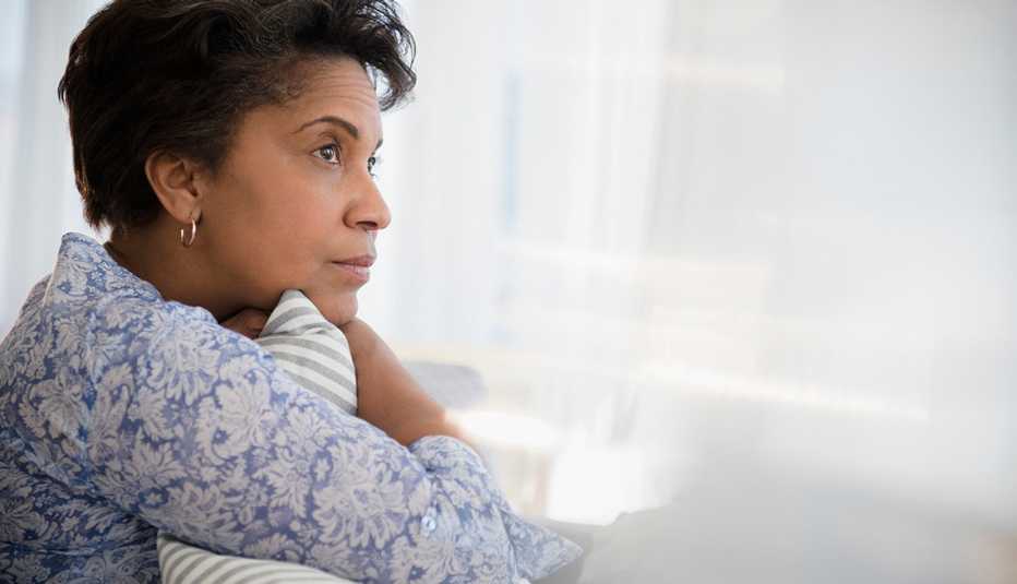 Mature woman clutching pillow in front of the window