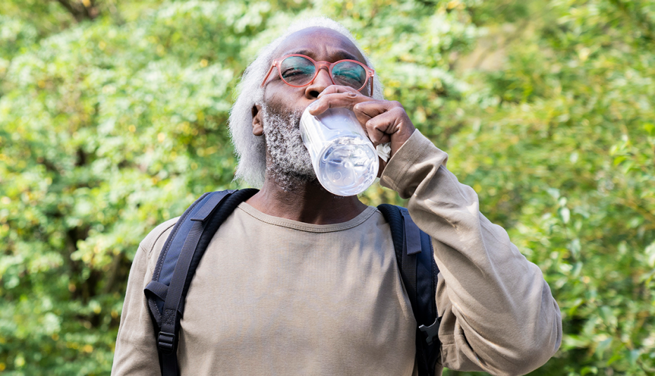 a man with a backpack drinking water to stay hydrated