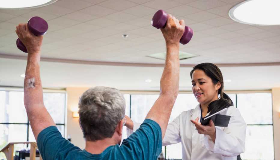 physical therapist helping patient lifting light weights