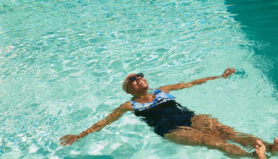 A woman floating alone in a large pool.