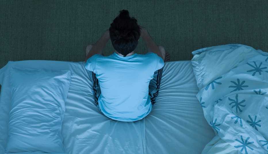 overhead view of a tired man sitting on the edge of his bed