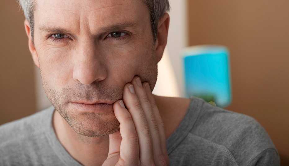 Man holding his jaw, looking like he is having tooth pain