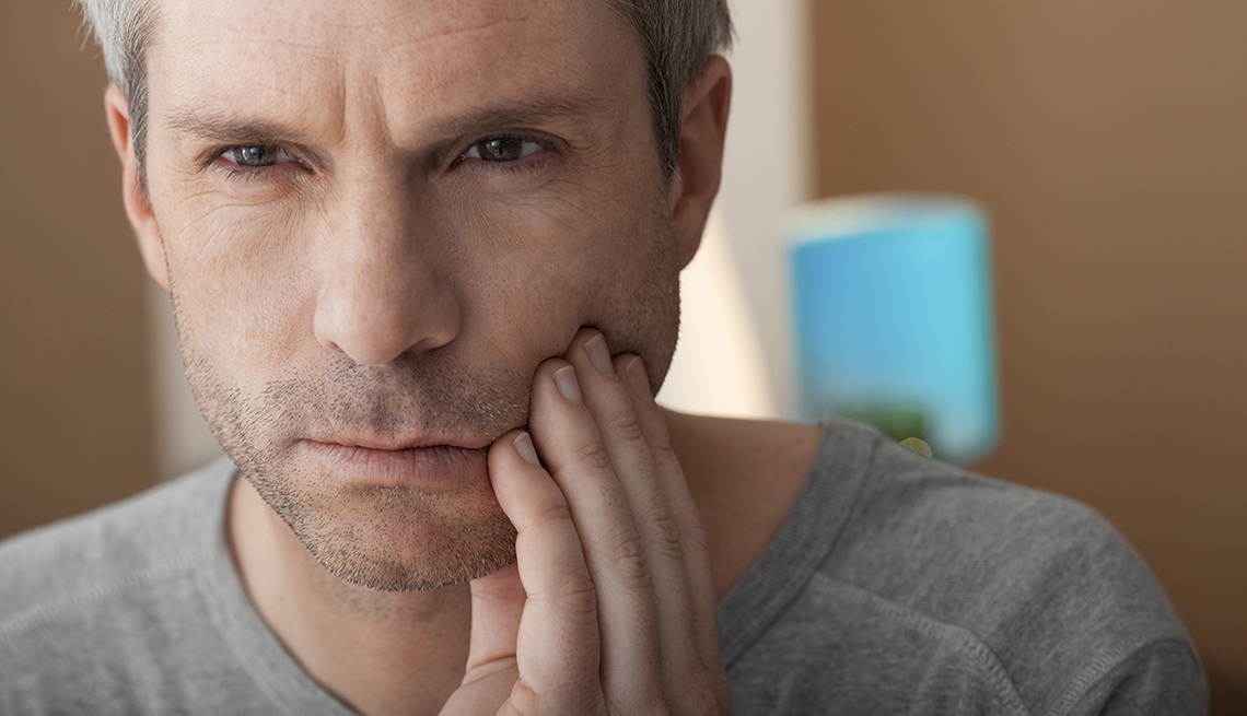 Man holding his jaw, looking like he is having tooth pain