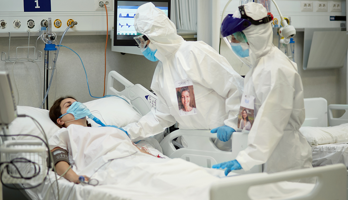 COVID-19 patient lying in a hospital bed with medical staff in protective suits nearby. 