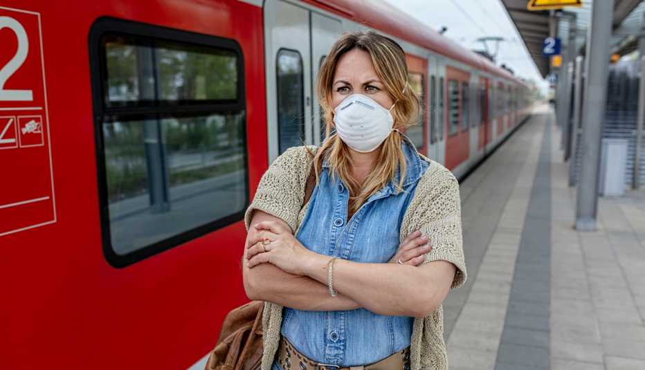 woman standing on a subway platform wearing an N95 face mask