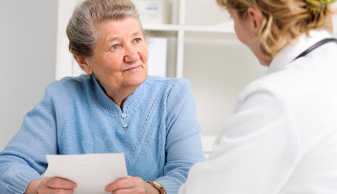 Woman holding a list of questions and talking to her doctor