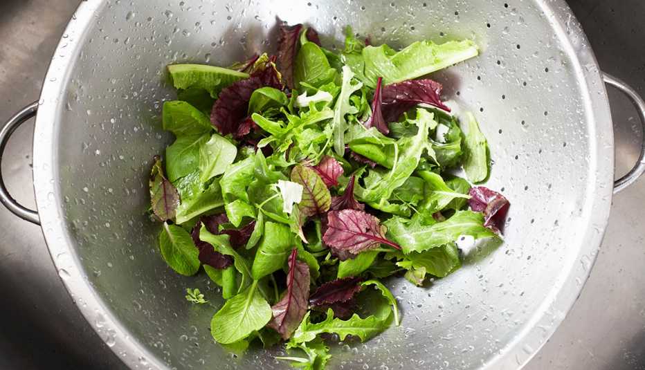 lettuce sitting in a silver strainer after being washed
