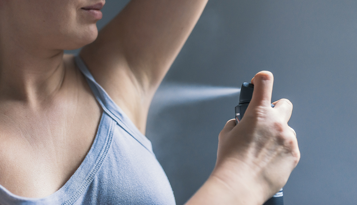 closeup of woman using underarm deodorant spray