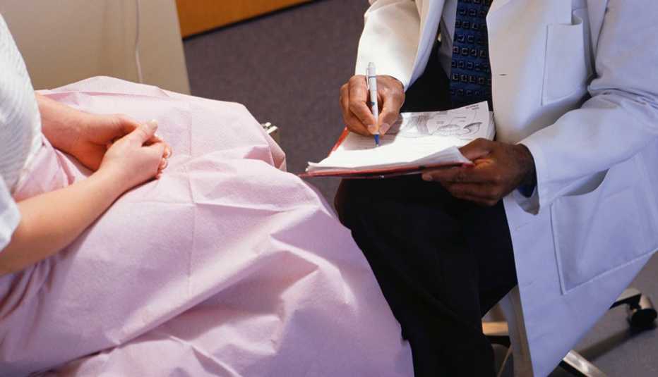 doctor writes on pad while talking with a female patient