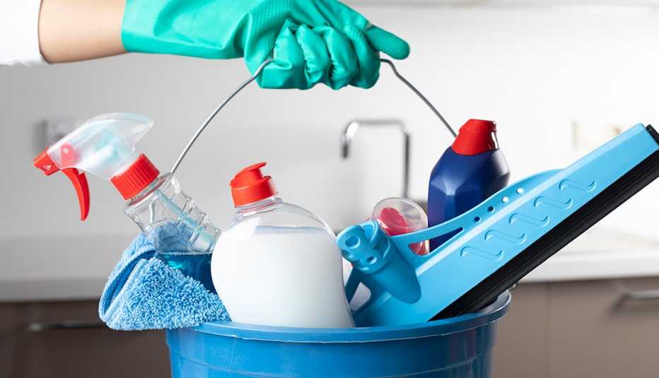 person holding bucket of cleaning products with gloved hand