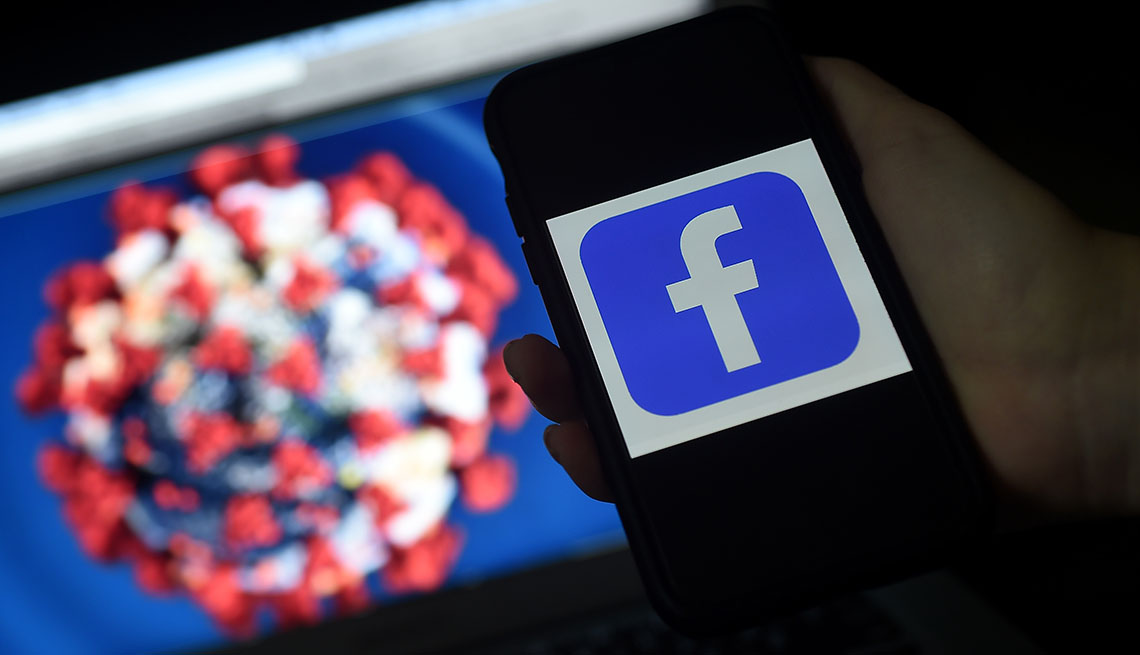 facebook logo on phone in front of a coronavirus illustration