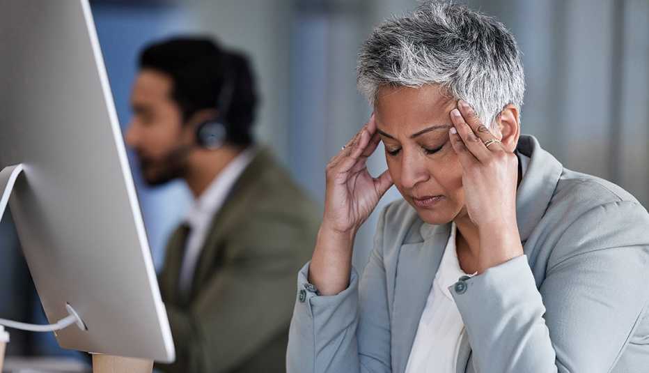 a businesswoman in a gray suit has a migraine and massages her temples