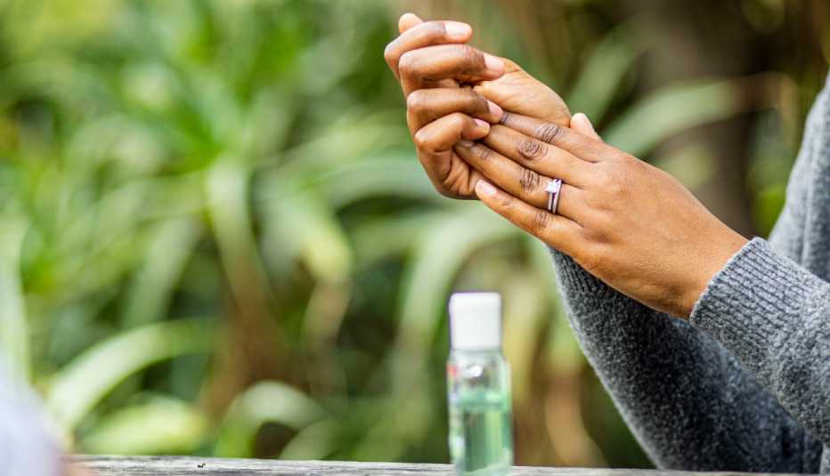woman outside rubbing hand sanitizer on her hands, the bottle of sanitizer sitting in front of her