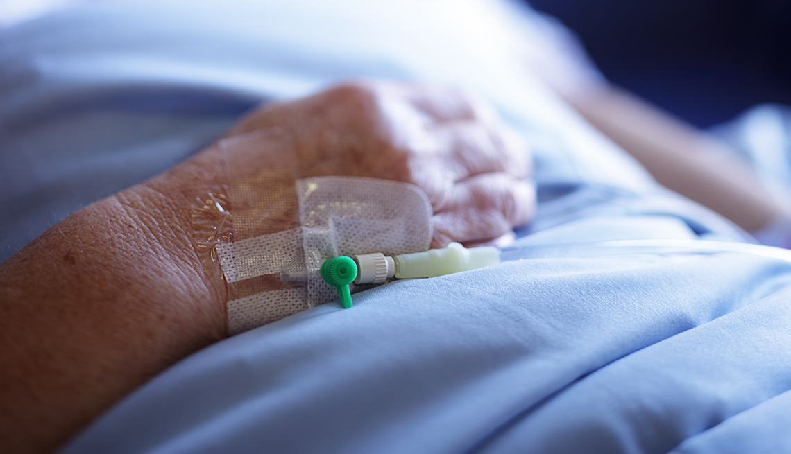 close up of a woman's hand with an iv tube, she is laying in a hospital bed